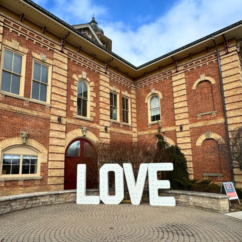 A white sign displaying the words love in capitalized letters is displayed in front of Orangeville's Town Hall